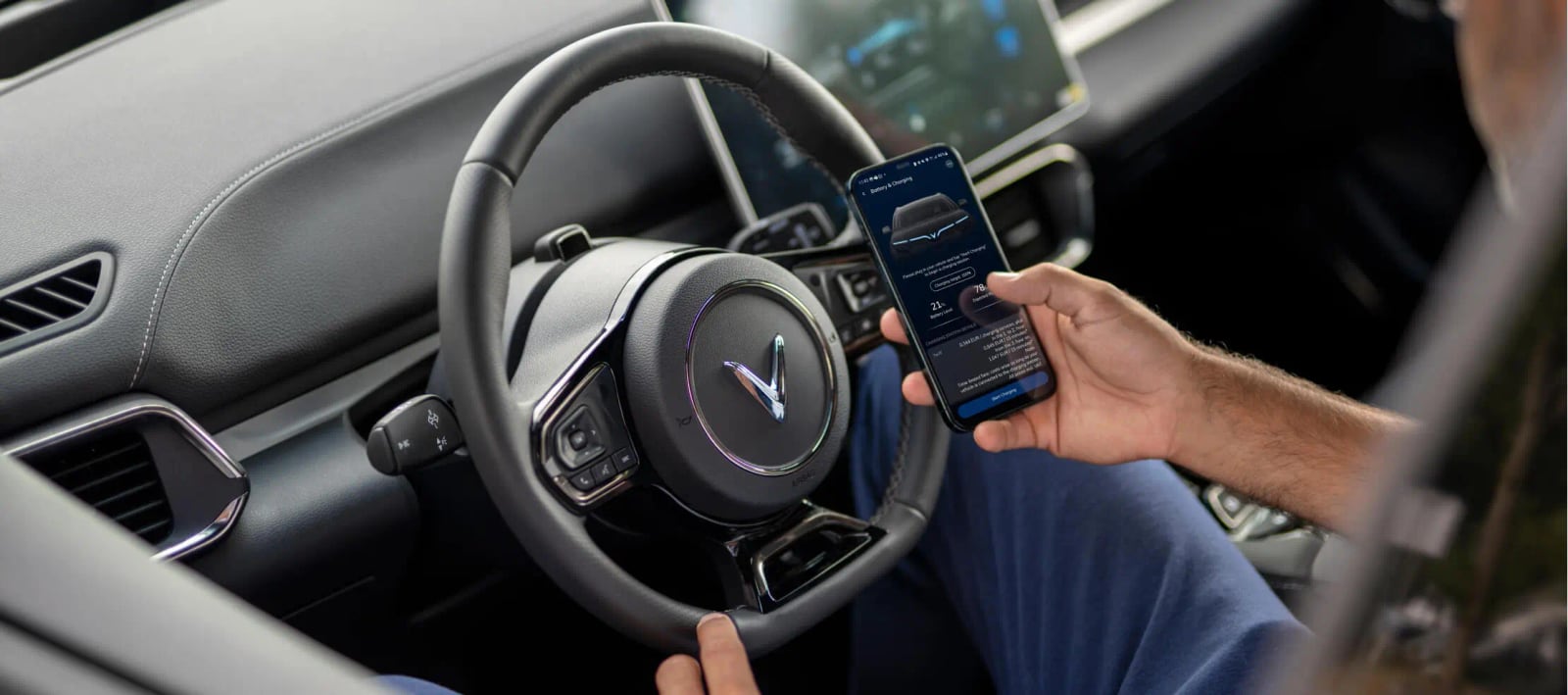 Driver holding a phone with the VinFast app inside a VF 8