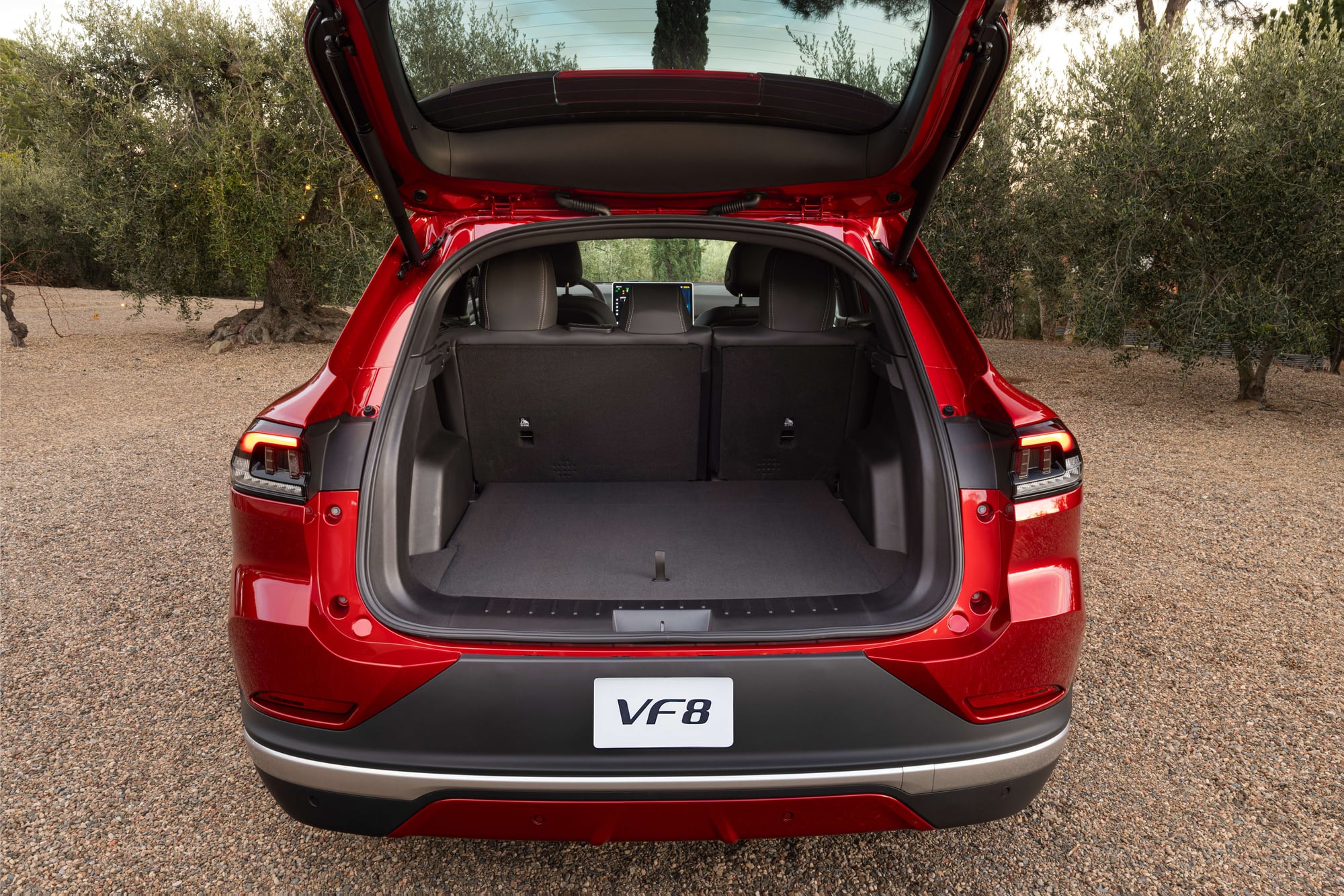VinFast VF 8 in red, rear three-quarter view with the power liftgate open showing the cargo area