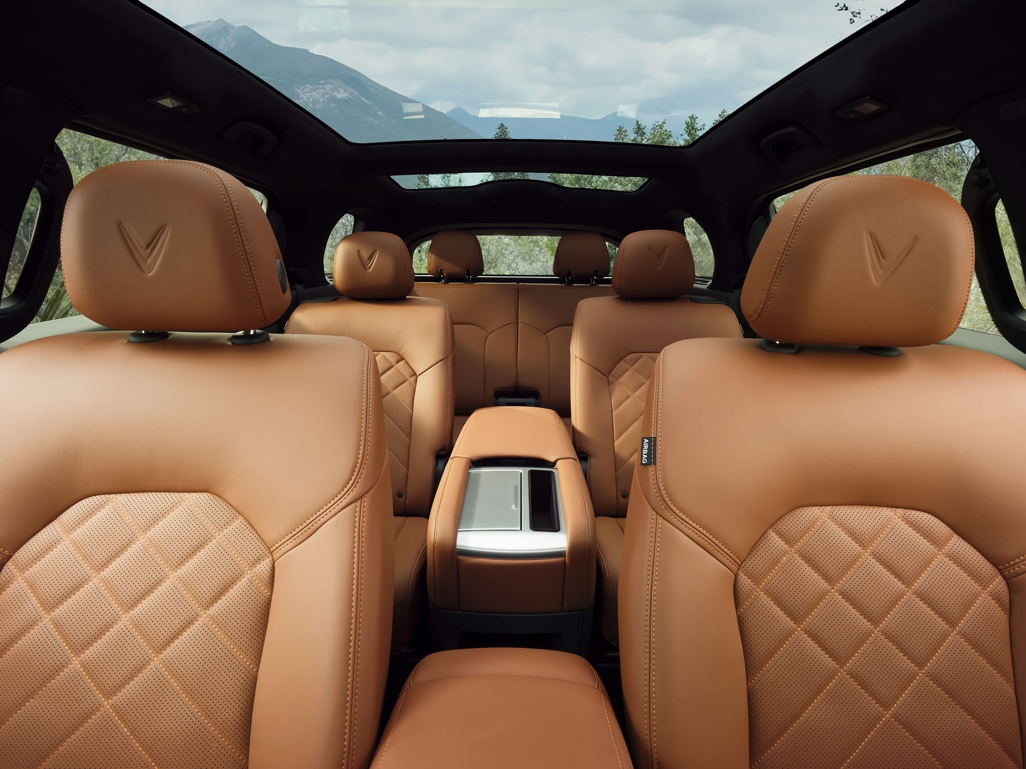 VinFast VF 9 second-row captain's chairs with the rear centre console, looking back through the glass roof